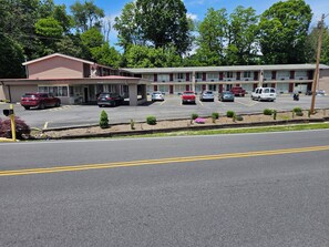 A motel with multiple parking spaces, a small garden area with shrubs, and a building with a flat roof. - The Edyn Hotel (Wytheville)