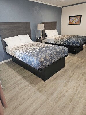 Two beds with patterned bedding, a nightstand with a lamp, and a wall map. - The Edyn Hotel (Wytheville)