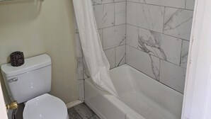 A bathroom with a toilet, shower, and towel rack. - The Edyn Hotel (Wytheville)