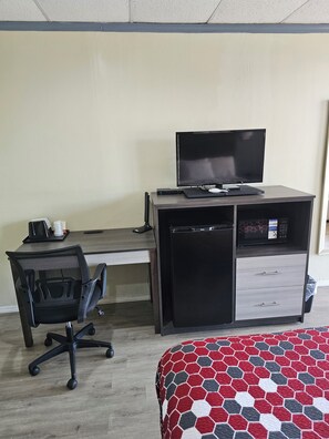 A hotel room with a desk, a black office chair, a bed with a red and white patterned bedspread, and a microwave. - The Edyn Hotel (Wytheville)
