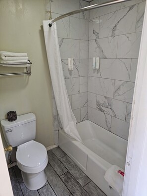 A bathroom with a toilet, shower, and towel rack.