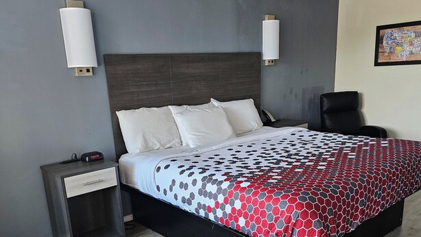 A modern hotel room with a large bed, a nightstand, a desk, and a chair. - The Edyn Hotel (Wytheville)