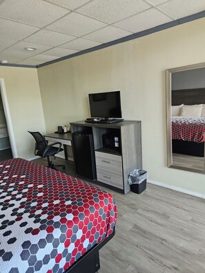 A hotel room with a bed, a desk with a computer, a chair, and a large mirror. - The Edyn Hotel (Wytheville)
