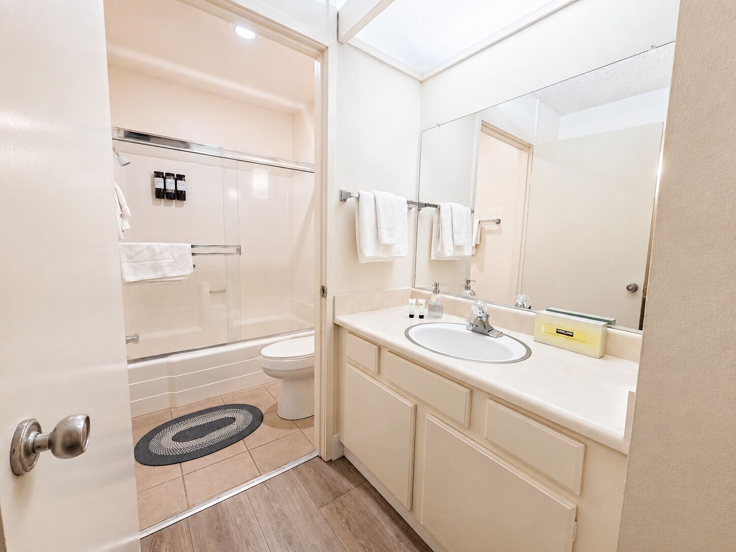 Een moderne badkamer met een glazen douchecabine, toilet, wastafel en spiegel.