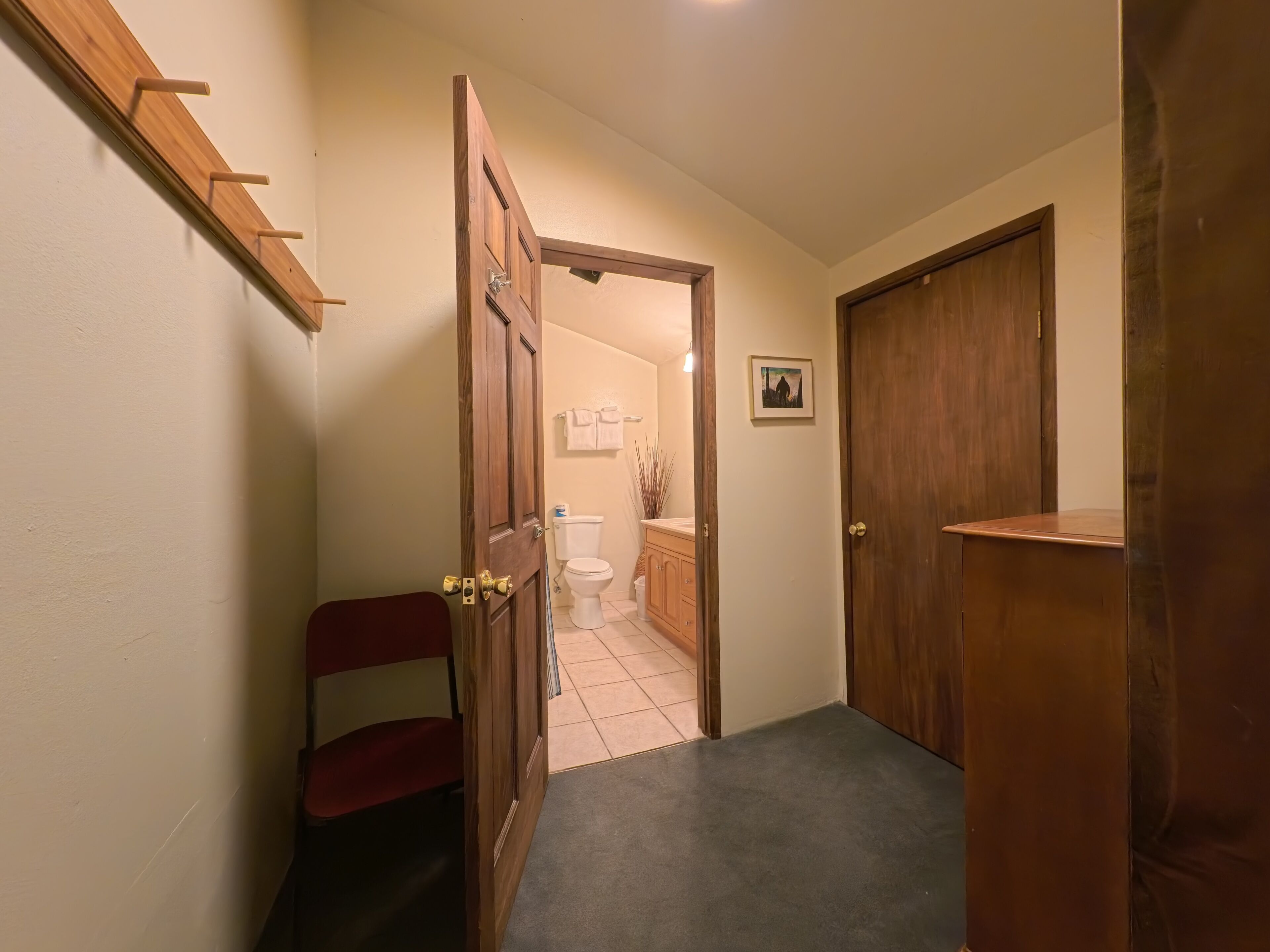 A hallway leading to a bathroom with a toilet, sink, and towel rack.