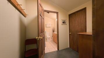 A hallway leading to a bathroom with a toilet, sink, and towel rack.