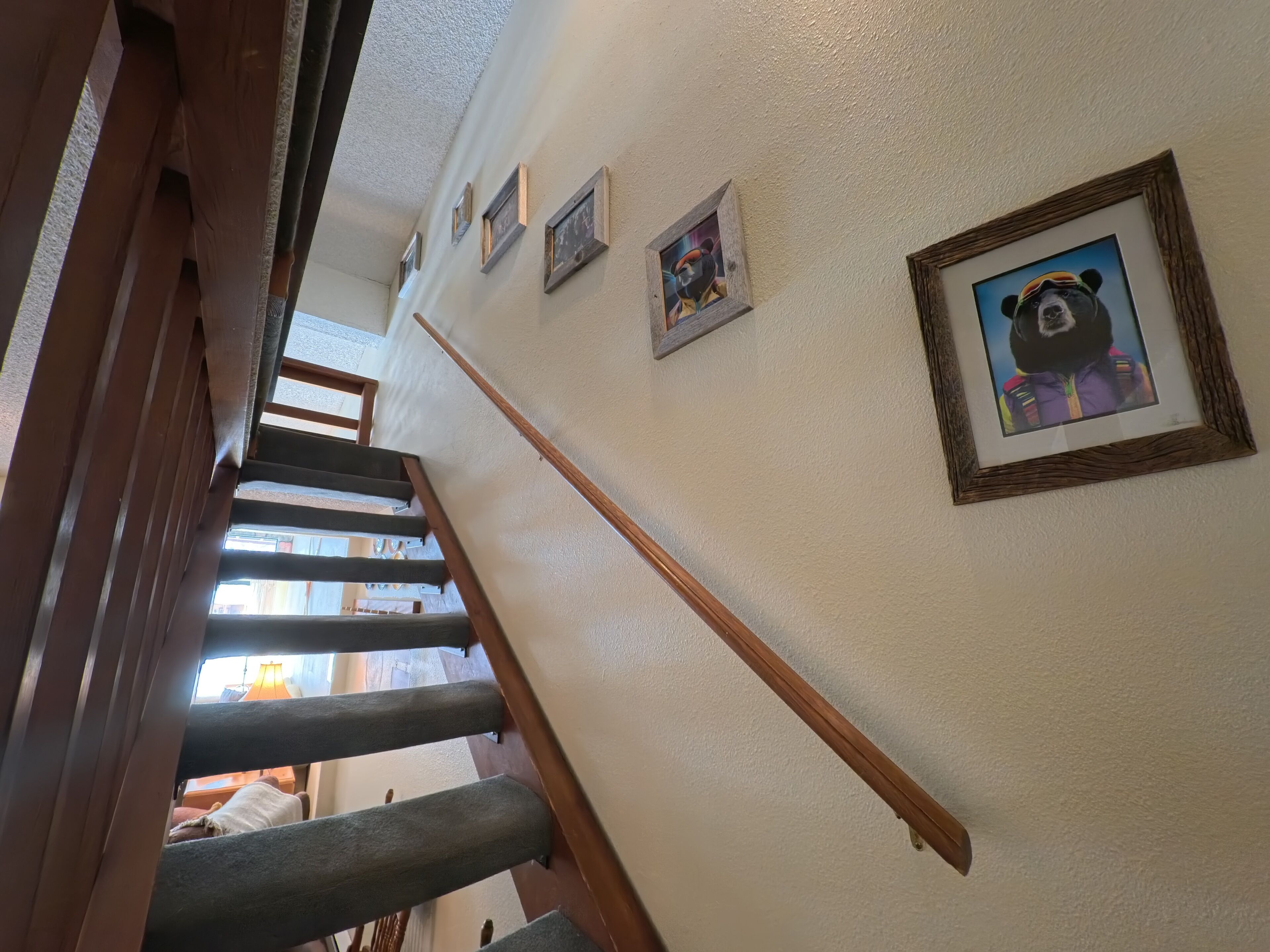 Een trap met houten leuningen en een muur met ingelijste foto's.