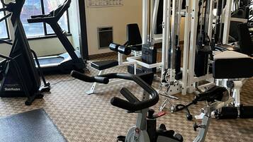 Un gimnasio con equipo de cardio, máquinas de pesas y una cinta de correr.