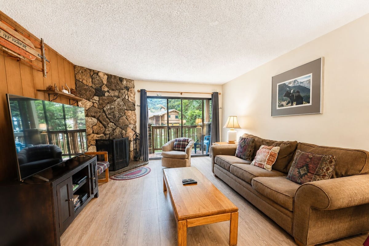 A living room with a stone wall, a fireplace, a television, a sofa, and a coffee table.