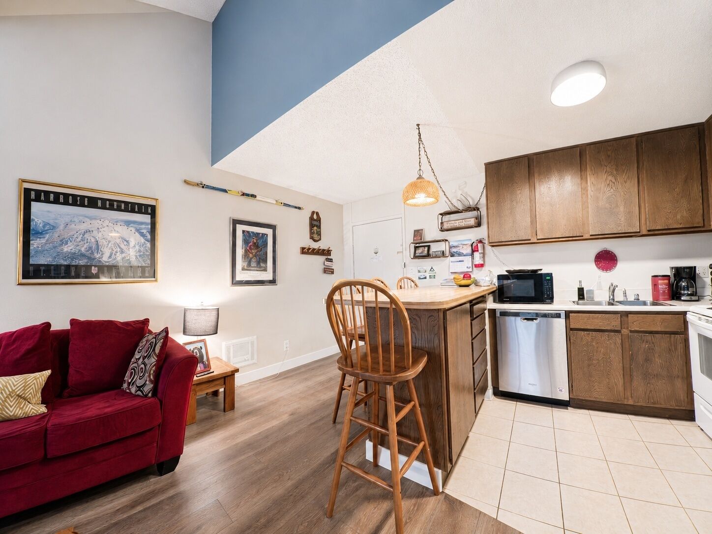 A compact living space with a kitchen, a dining area, and a red sofa.