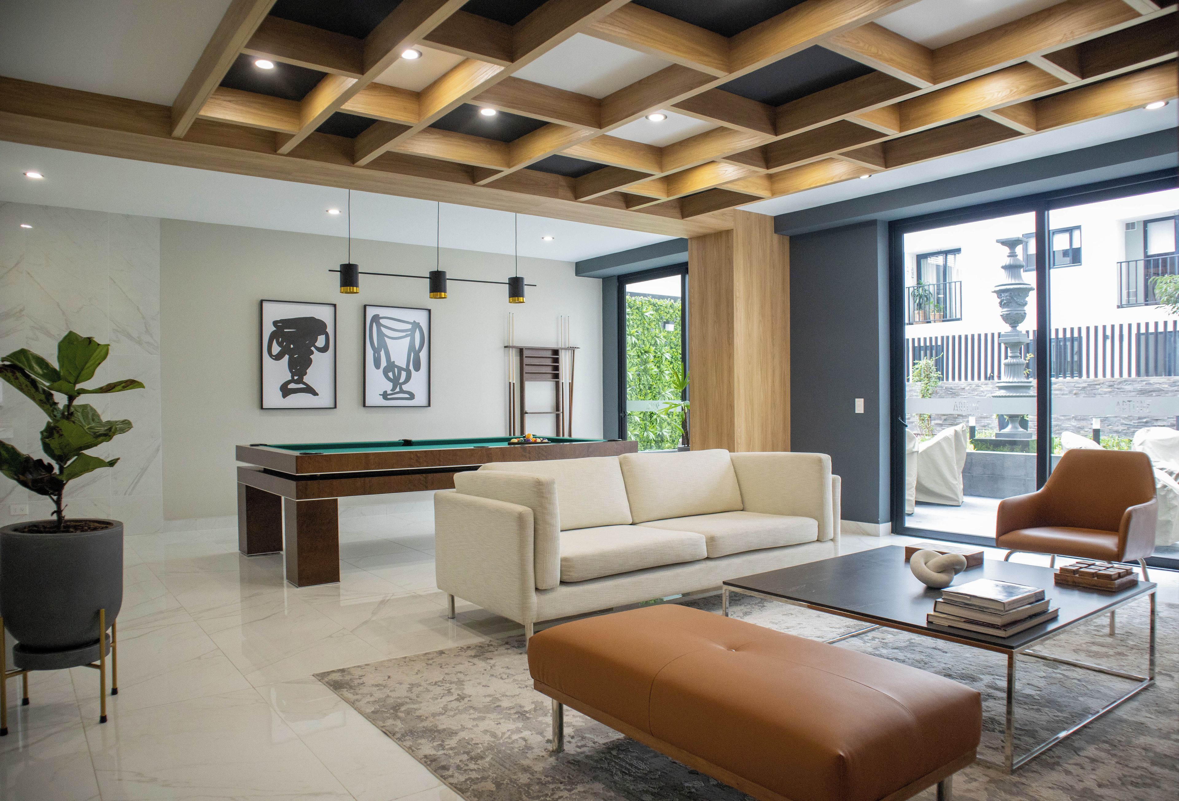 A modern living room with a pool table, a sofa, a coffee table, and a large window offering a view of the outside.