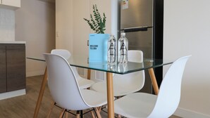 A modern kitchen with white cabinetry, a stainless steel refrigerator, and a glass-top dining table with white chairs. - Artline by Wynwood House (Lima)