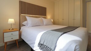 A neatly made bed with a headboard, a bedside table with a lamp, and a wardrobe. - Artline by Wynwood House (Lima)