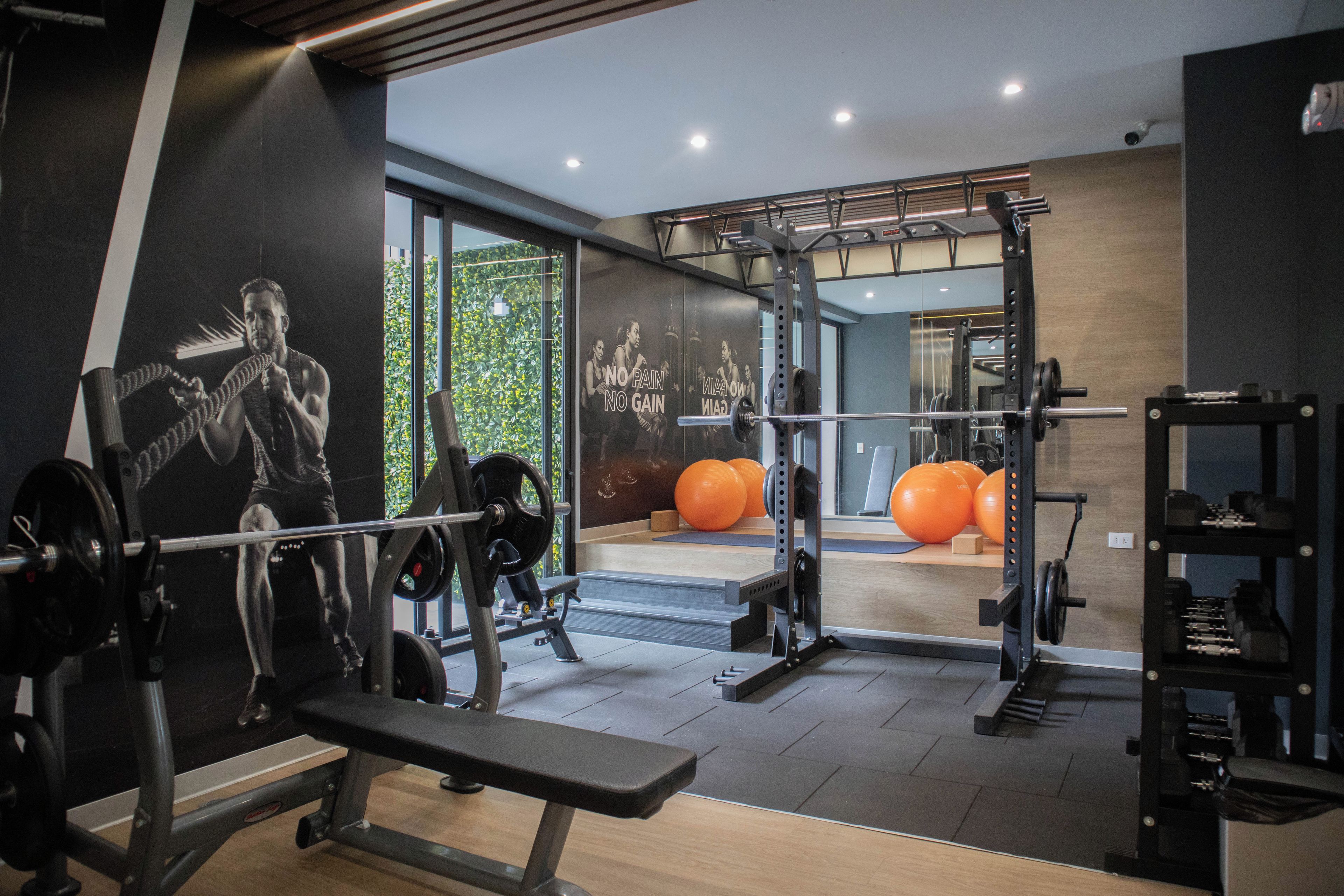 Een sportschool met diverse trainingsapparaten, een bank en een muur met motivatieposters.