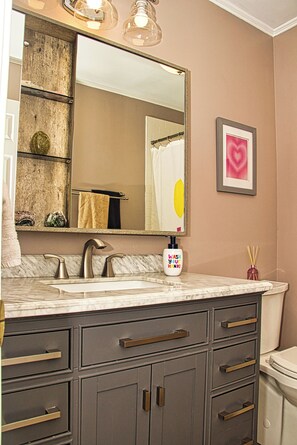 A bathroom with a marble sink, a large mirror, and a towel rack.