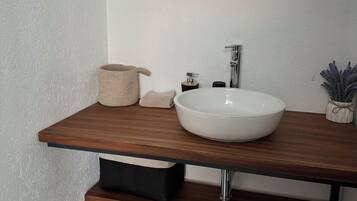 A modern bathroom with a wooden vanity, a round mirror, and a white sink.