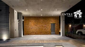 A modern building entrance with a brick wall, concrete pillars, and a car parked outside.