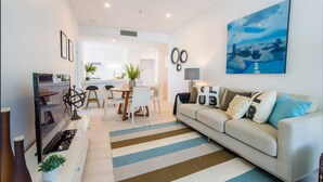 Un salon moderne avec un canapé, un téléviseur et un coin repas.