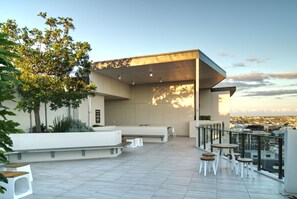 A rooftop terrace with seating areas, a view of the city, and a modern architectural design.