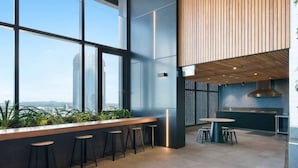 A modern interior with a bar area, seating, and a kitchen. - 2BR Luxury Skytower Views CBD Pool Gym Netflix (Brisbane)