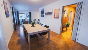 Un comedor con una mesa y sillas de madera, una planta en maceta y obras de arte en las paredes.