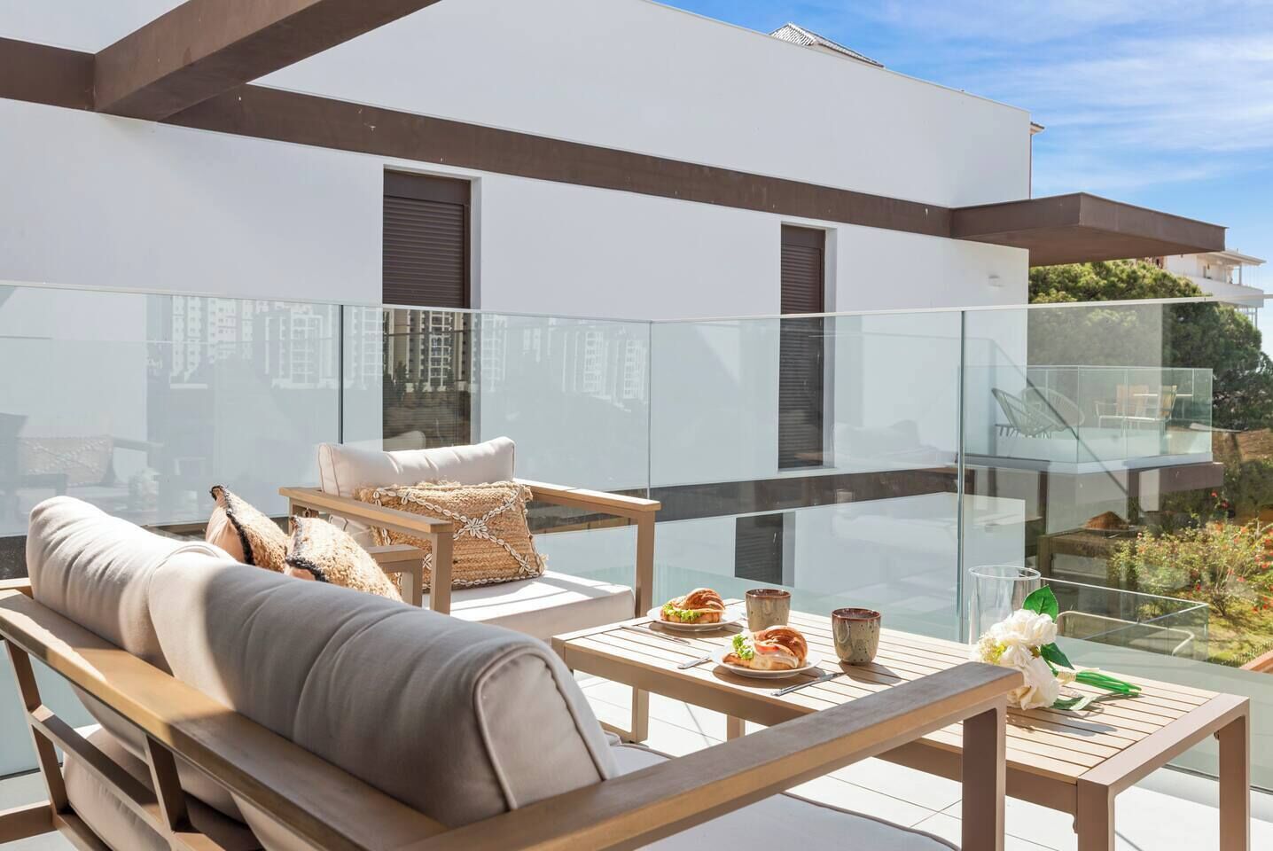 A modern outdoor seating area with a sofa, chairs, and a table set for dining.