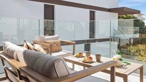 A modern outdoor seating area with a sofa, chairs, and a table set for dining.
