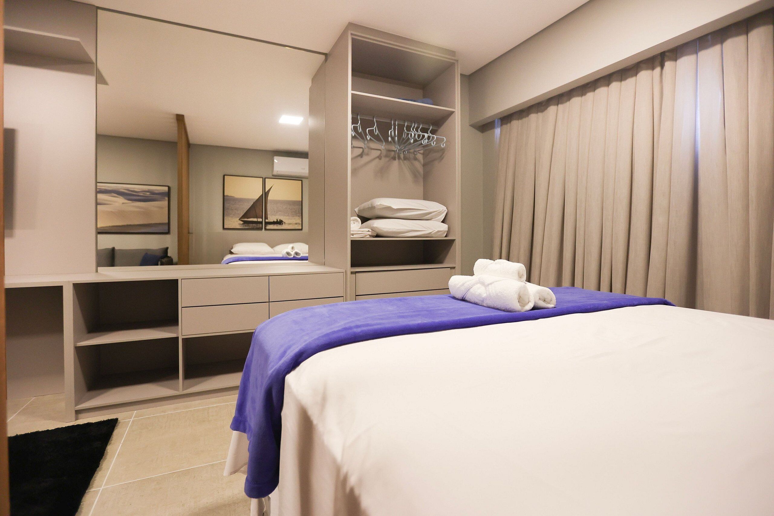 A hotel room with a bed, a wardrobe, a desk, and a mirror.