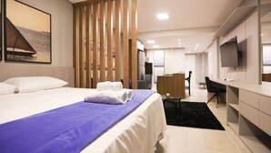 A modern hotel room with a large bed, a desk, a TV, and a view of the sea. - Studio Shopping OKA Floripa - SOK132 (Florianopolis)