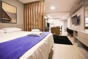 Une chambre d’hôtel moderne dotée d’un grand lit, d’un bureau, d’une télévision et offrant une vue sur la mer.