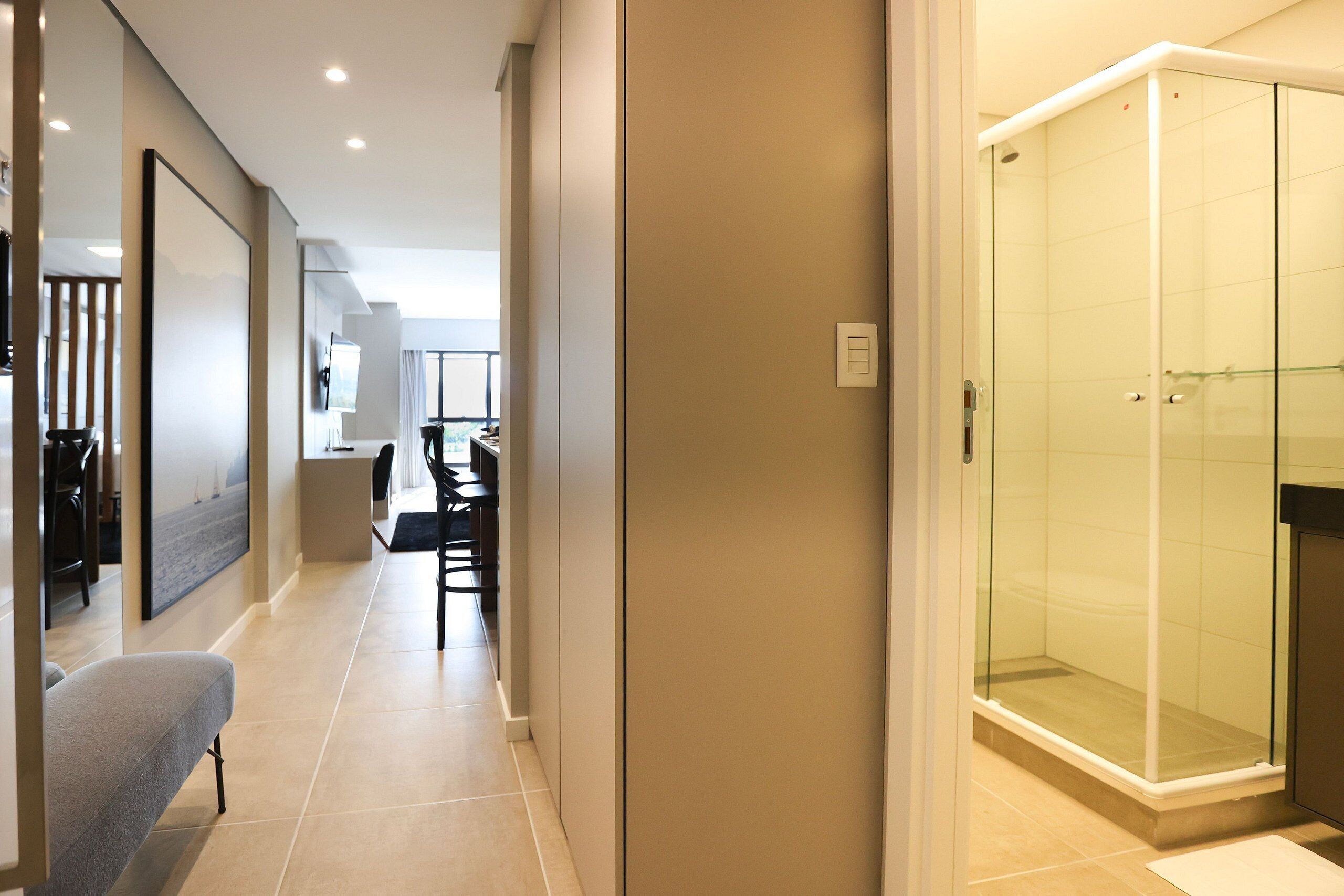 Een moderne hotelgang met een douchecabine van glas, een zithoek met een bank en een eethoek.