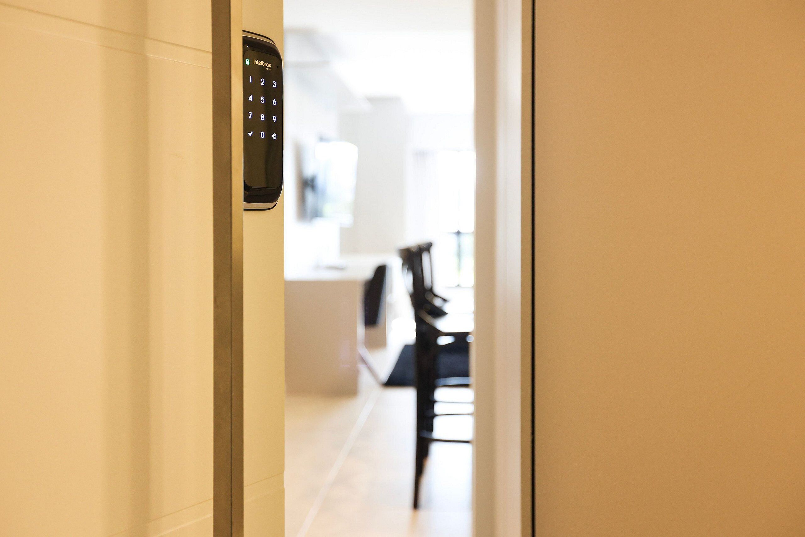 A hallway with a digital keypad door lock, leading to a dining area with a table and chairs.