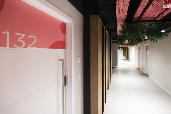 A corridor with a door labeled '132' and a hanging plant.