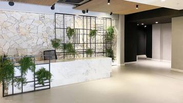 A modern lobby with a stone wall, a reception desk, and a staircase.