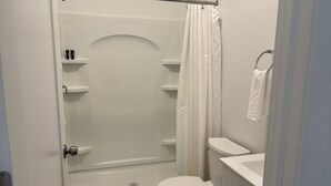 Une petite salle de bain moderne équipée d’une douche, de toilettes et d’un porte-serviettes.