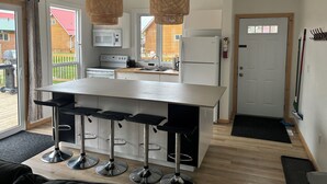 Une cuisine moderne dotée d’un îlot central, de tabourets de bar et de luminaires suspendus en rotin.