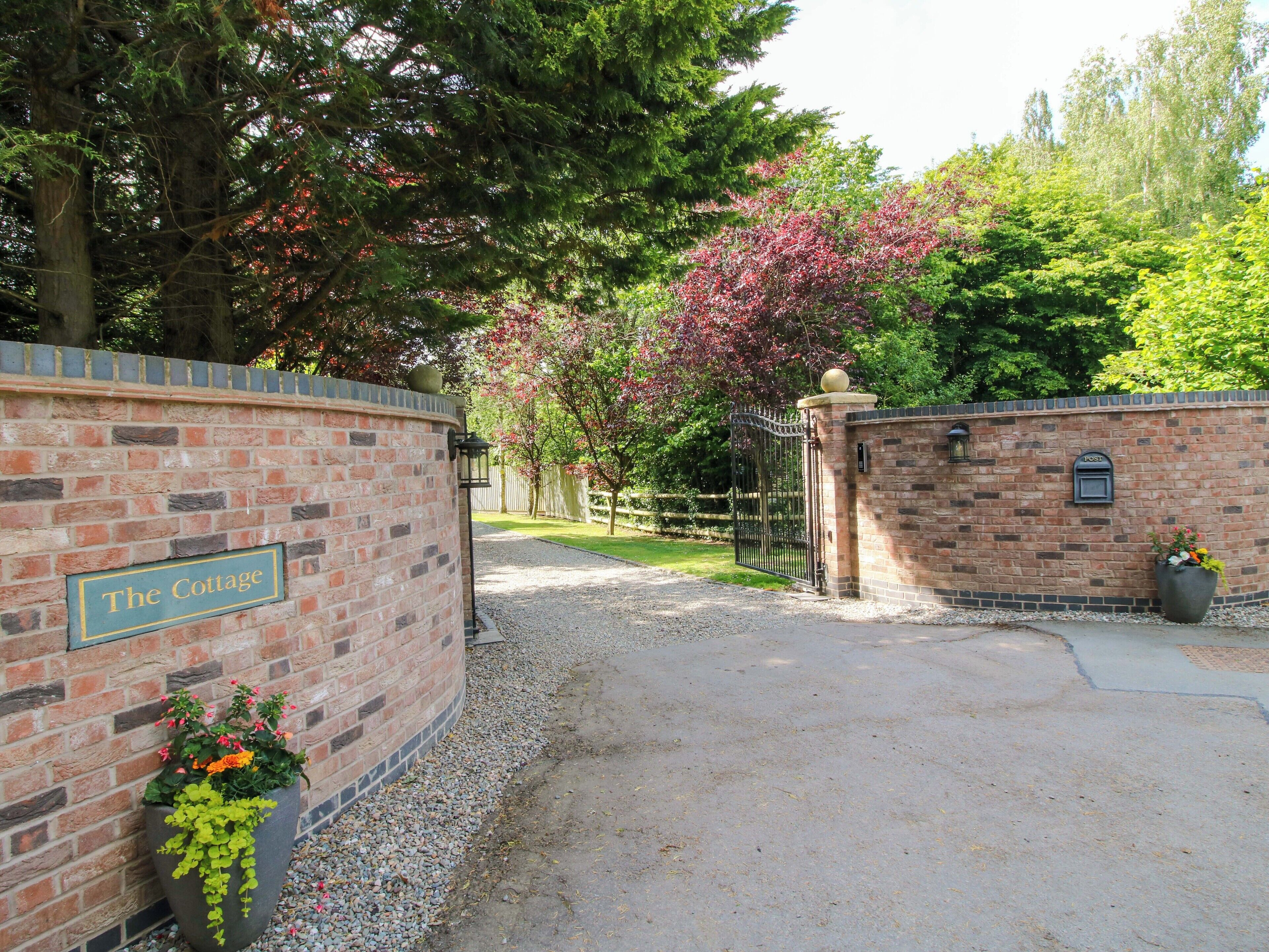 A brick wall with a sign reading "The Cottage" and a mailbox.