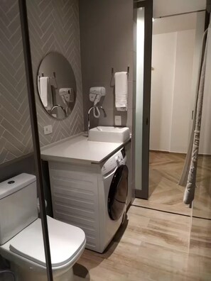 A modern bathroom with a toilet, sink, and washing machine.