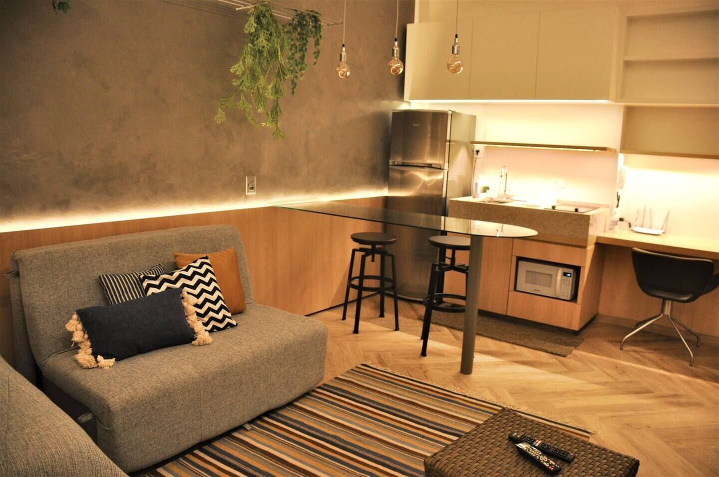 A modern living room with a grey sofa, a striped rug, and a remote control on a coffee table.