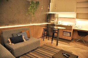 A modern living room with a grey sofa, a striped rug, and a remote control on a coffee table.