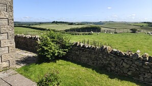 A stone wall with a grassy area and a stone building. - Bush Nook House (Brampton)