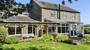 A stone house with a large glass conservatory and a wooden deck. - Bush Nook House (Brampton)