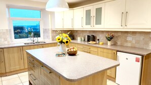 A kitchen with a large island, wooden cabinets, a built-in oven, and a window with a view. - Bush Nook House (Brampton)