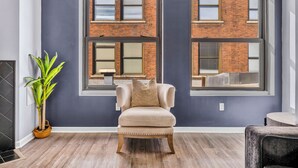 A room with a large window, a chair, and a potted plant. - Charming loft in lovely DT Cleveland - Free parking - Balcony - Gym (Cleveland)