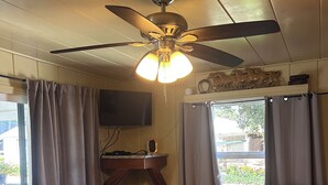 A room with two beds, a ceiling fan, a desk with a chair, a television, and a window with curtains. - Tranquil studio with WiFi in sunny outskirts Salinas (Salinas)