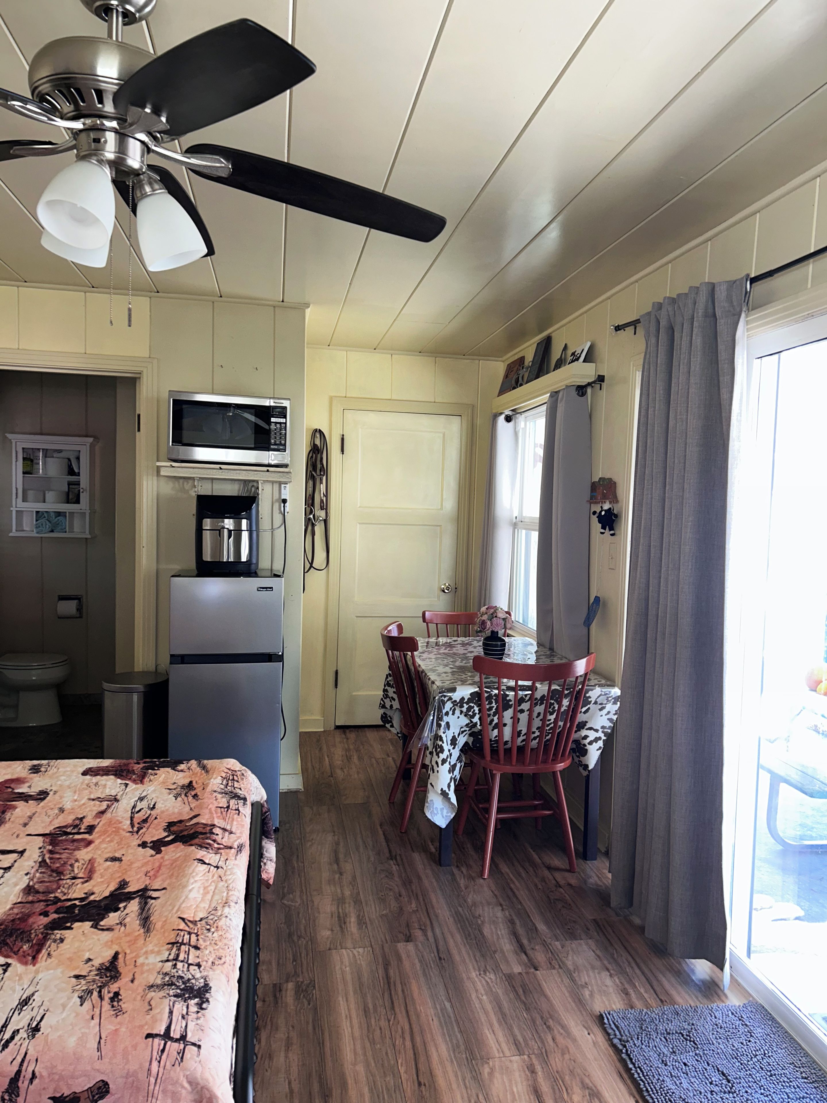 A compact kitchen with a microwave, refrigerator, and ceiling fan.