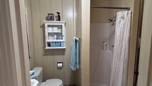 A compact bathroom with a toilet, sink, shower, and a small cabinet with toiletries. - Tranquil studio with WiFi in sunny outskirts Salinas (Salinas)