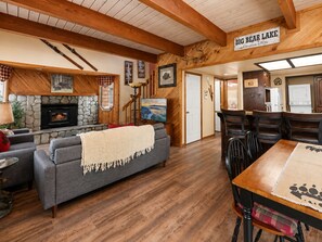 Een gezellig interieur met een stenen open haard, een eethoek met houten stoelen en een bordje met de hoogte van Big Bear Lake.