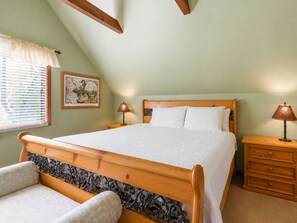 Een slaapkamer met een houten bed, een nachtkastje, een lamp, een stoel en een raam met jaloezieën.
