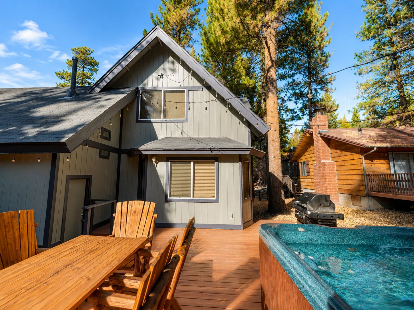 A two-story cabin with a deck, outdoor seating, and a hot tub.